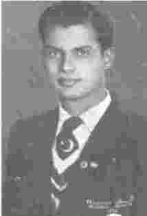 A man in suit and tie standing next to a wall.